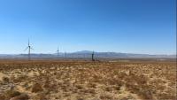 Desert landscape with renewable energy equipment in the background.