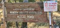 Sign for Hunter Valley Road. It  is an old, weather beaten, wood sign with thick yellow letters.