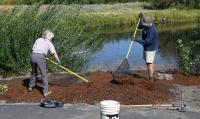 Two people using tools to work soil at a volunteer event