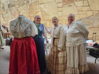 Living historians pose next to women's frontier fashion display. 