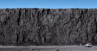 Huge coal wall at the Powder River Basin with worker wearing hardhat and truck at the base of it in Wyoming
