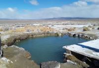 A pool of water on desert floor near wooden boards.