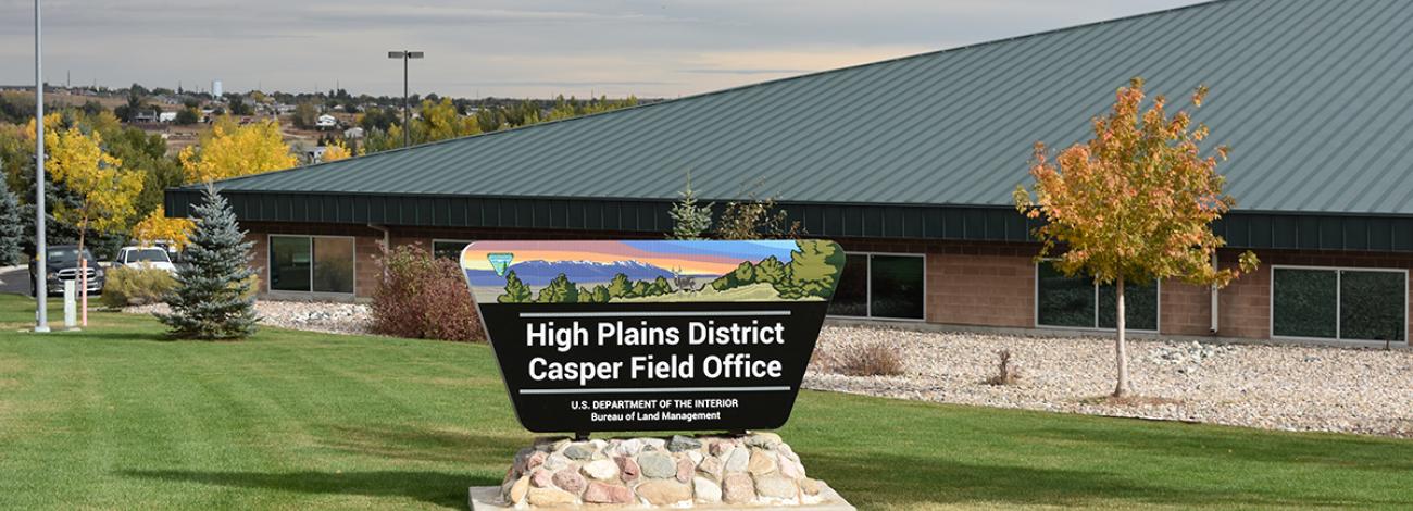 The road sign for the High Plains District Office, with the building, fall foliage and the City of Casper in the background.