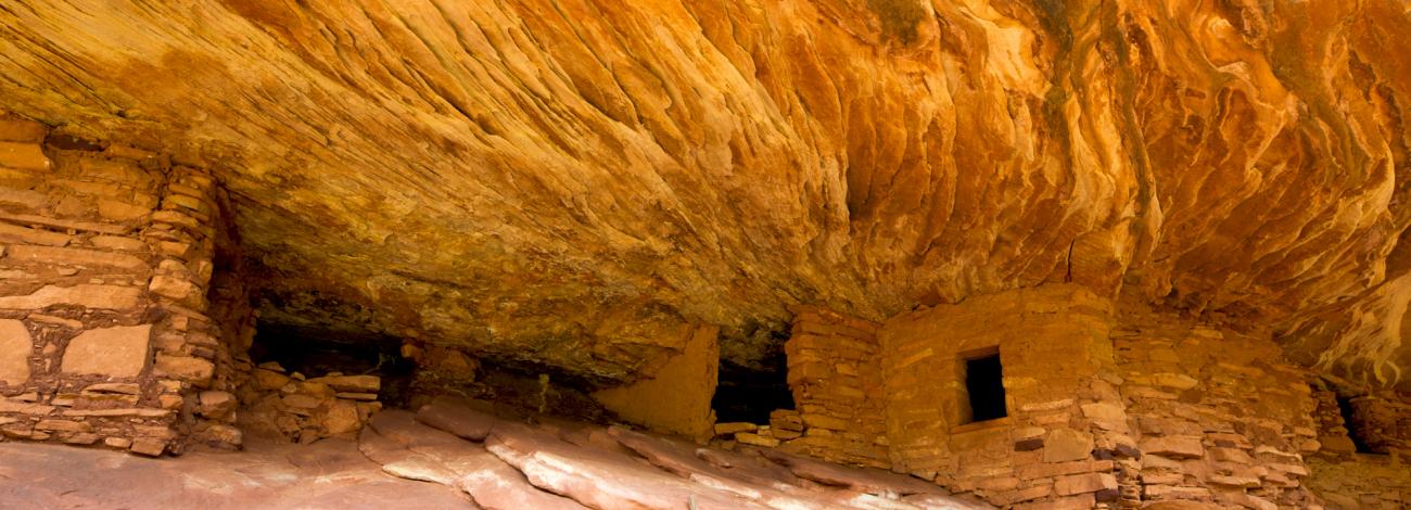 House on Fire, an archeological site within Bears Ears National Monument — a constructed stone structure, located in an alcove with distinct ribbons of sandstone creating a flame-like appearance. 