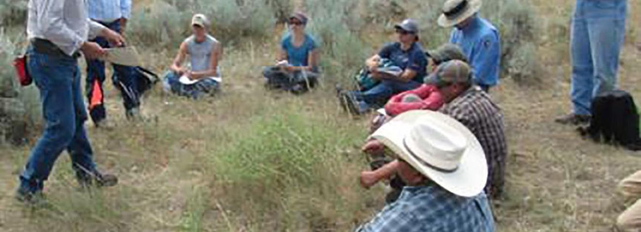 photo of people listening to someone in a field