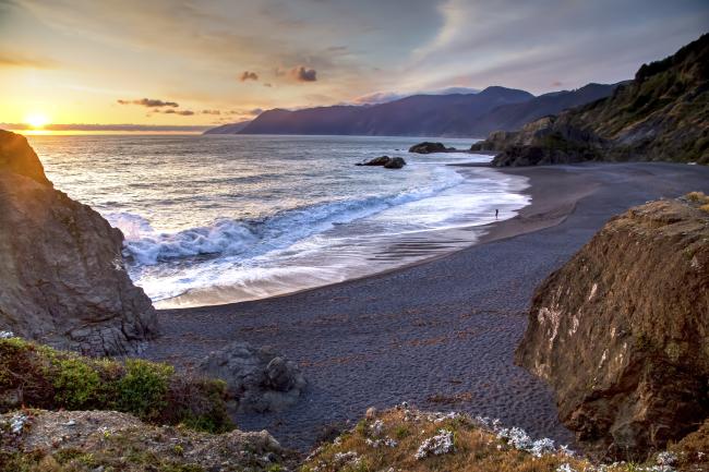 sunset at a rocky beach with a mountain range