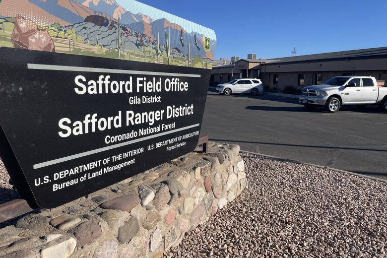 Trapezoidal sign outside of an office building near a parking lot.
