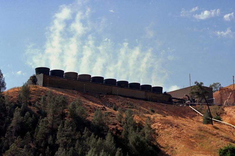 Steam shoots up from a geothermal plant located at the top of a hill.