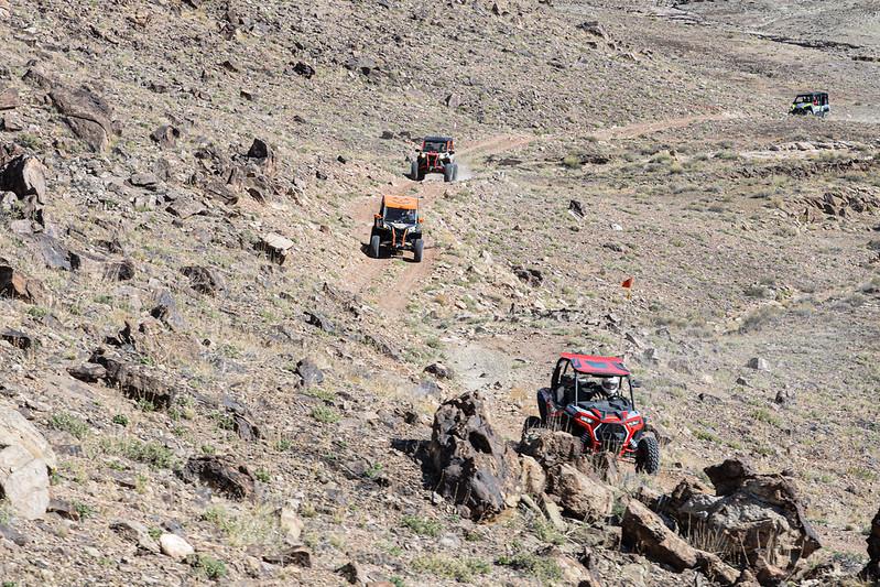 OHVs driving in a caravan on a remote, dirt road.