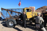 Owner stands in front his large off-road tow truck.