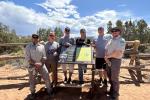 A small group poses around a newly installed informational sign