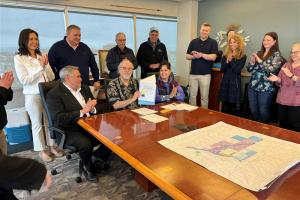 Group of people around a man holding a patent document.