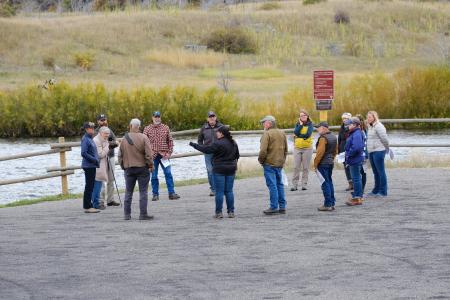 A group of about 10 people stand in a circle near a river.